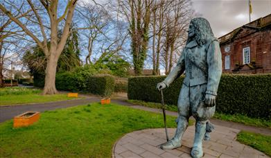 An historic statue that's turned green in the weather in a green garden village