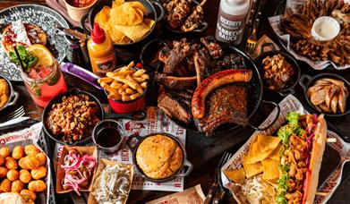 Table showing various Hickory's Smokehouse dishes including steak, hotdogs and coleslaw.