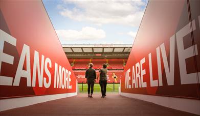 Two people walking out onto the pitch at Anfield