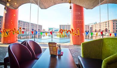 The view through a brightly decorated window, to the Royal Albert Dock on a sunny day.
