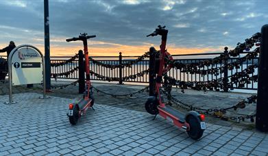 Two voi electric scooters on the waterfront overlooking the river