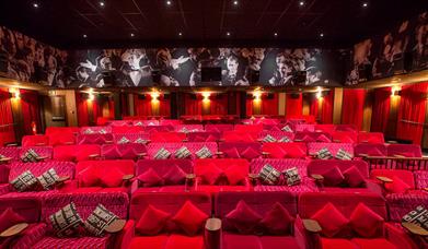 Plush red couches in a dimly lit cinema